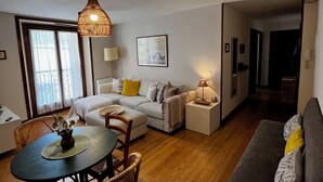 Un salon comprenant un canapé, une table à manger avec des chaises, un luminaire suspendu et un tableau encadré accroché au mur.