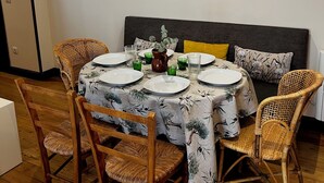 Un coin repas avec une table ronde dressée pour quatre personnes, entourée de chaises en osier.