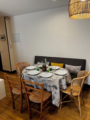 A dining area with a round table set for four, surrounded by wicker chairs.