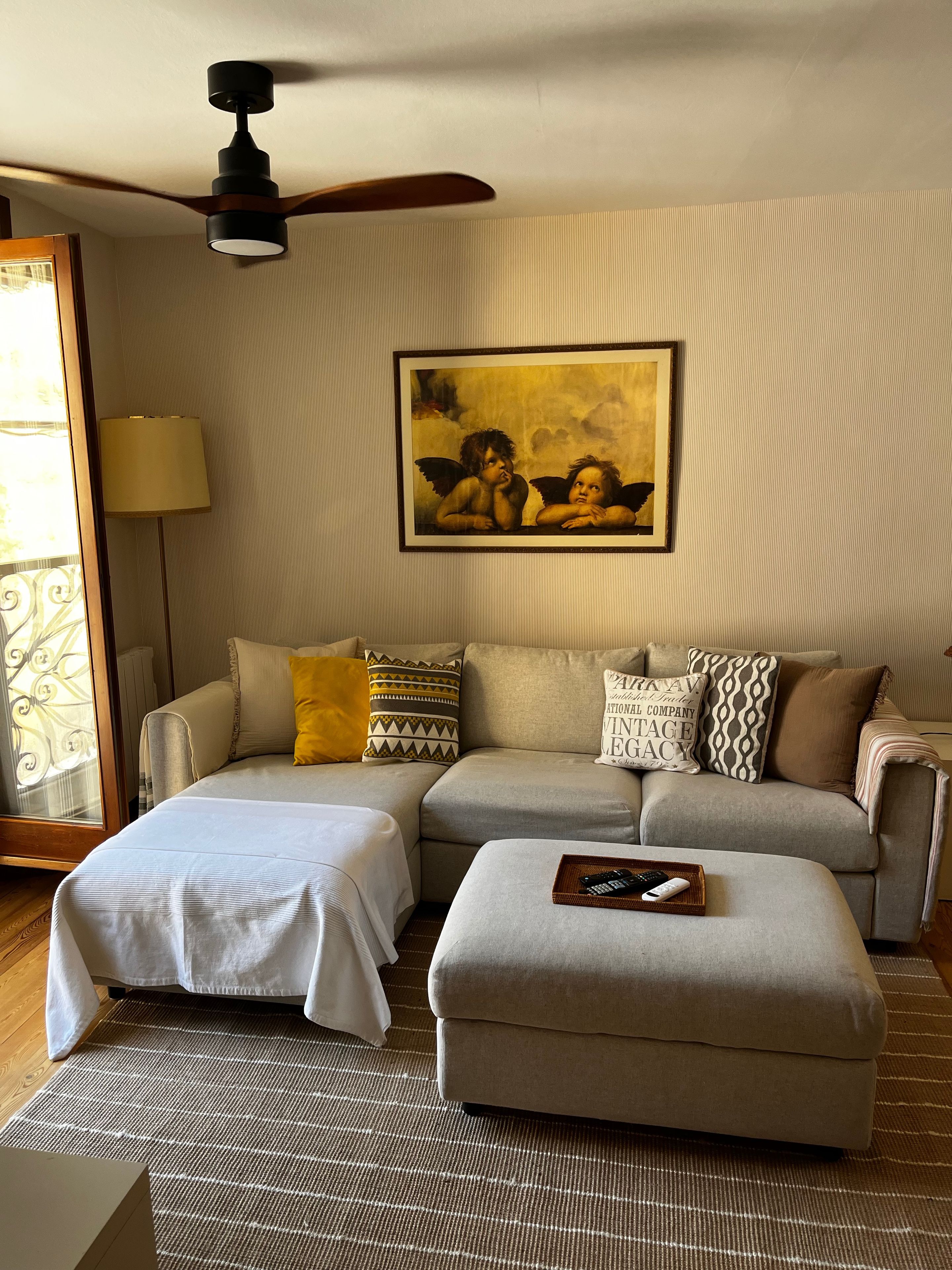 A living room with a sofa, ottoman, and a ceiling fan.