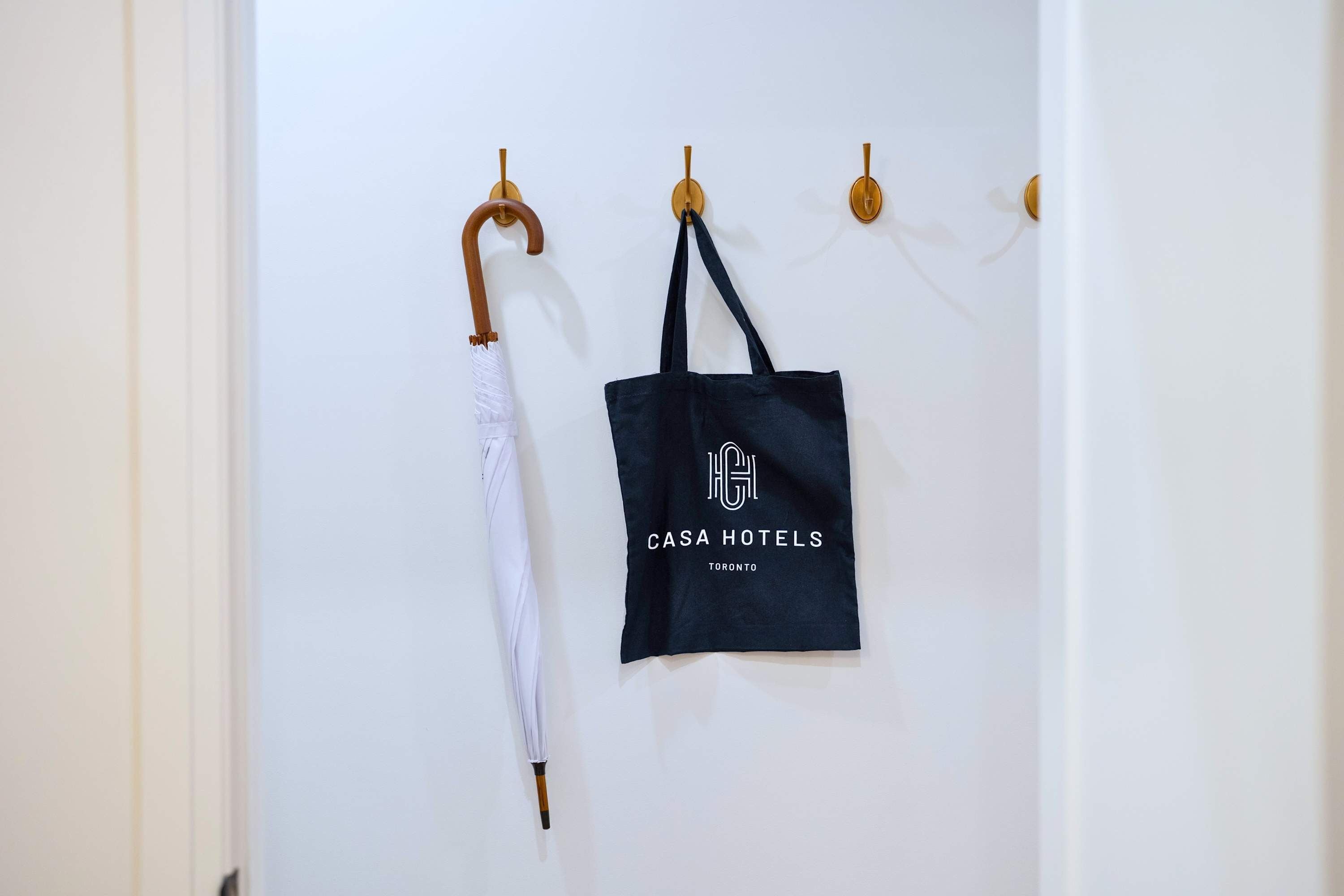 A wall with a white umbrella and a black tote bag hanging on hooks.