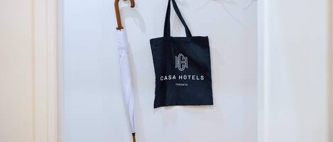 A wall with a white umbrella and a black tote bag hanging on hooks.