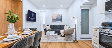 A modern hotel room with a dining area, a sofa, a kitchen, and a living area.