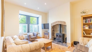 A cozy living room with a fireplace, a sofa, a coffee table, and a bookshelf.