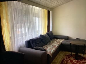 A living room with a sofa, a small round table, and a patterned throw. - Vacation apartment/ accommodation for up to 7 persons Bodenwerder (Bodenwerder)