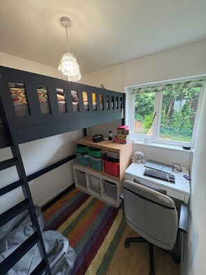 A bunk bed with storage drawers, a desk with a chair, a computer, and a window with a view of greenery. -     Comfortable Family Home Near the River (Henley-on-Thames)