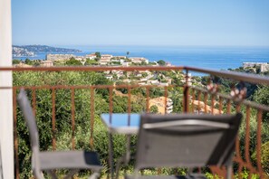 Un balcon donnant sur une ville côtière, avec une chaise et une table.