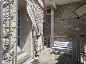 Un edificio de piedra con una reja de metal, un banco y una ventana.