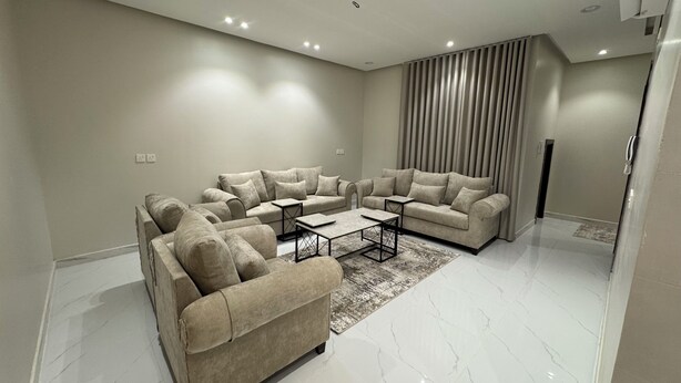 Una sala de estar moderna con un sofá seccional, una mesa de centro y un gran ventanal con cortinas.