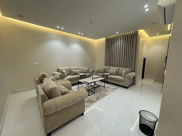 A modern living room with a sectional sofa, a coffee table, and a wall-mounted TV.