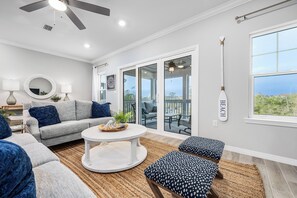 A modern living room with a grey sofa, a round coffee table, and a view of the outdoors through large sliding glass doors.