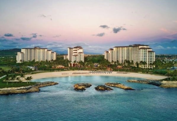 A coastal resort with multiple high-rise buildings, a sandy beach, and a clear view of the ocean.