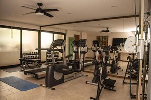 Un gimnasio con máquinas de cardio, equipo de levantamiento de pesas y mancuernas.