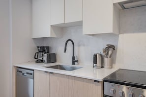 Eine moderne Küche mit Geschirrspüler, Kaffeemaschine, Toaster, Spüle und Herd.