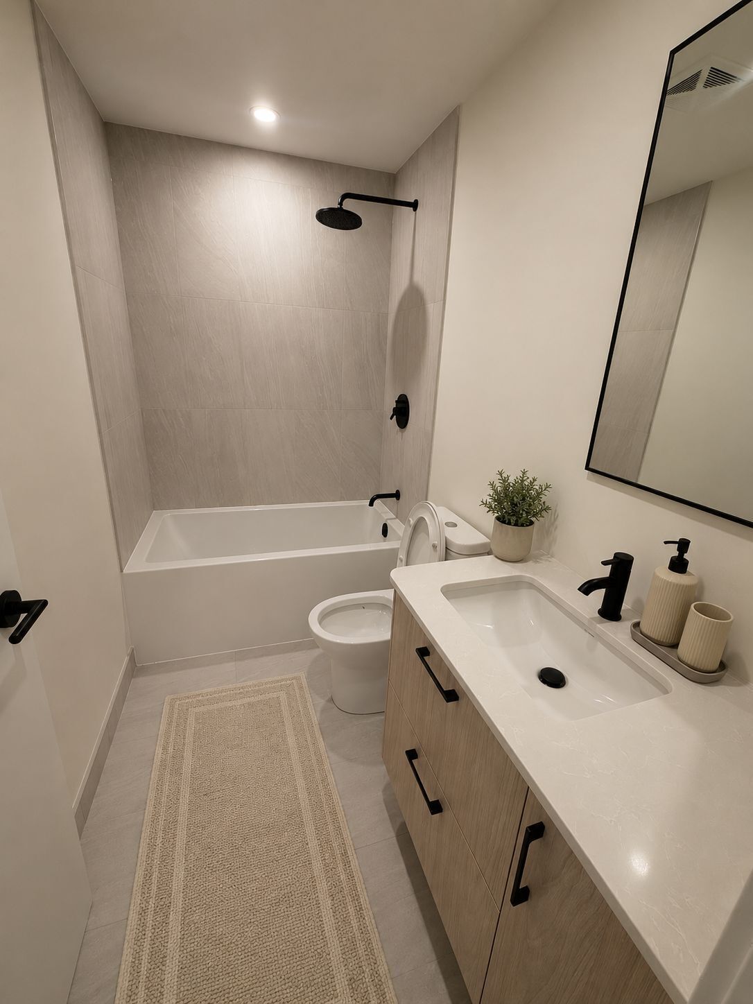 Un baño moderno con bañera, inodoro, lavabo y espejo.
