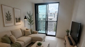 A modern living room with a sofa, coffee table, TV, and a balcony with a city view. - Elegant 1+1bed 1bath |Sauna|Gym | Cold plunge (Toronto)