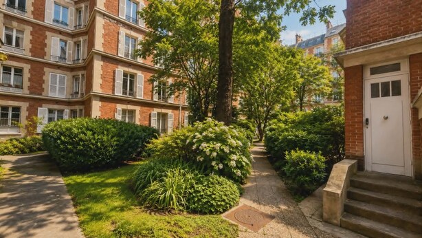 A multi-story residential building with a brick facade, a central garden with various shrubs and a pathway, and a white door on the right. - Charming Apt Steps from Eiffel Tower & Quai Branly (Paris)