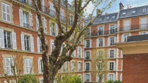 A multi-story residential building with a courtyard garden, visible balconies, and a brick facade. - Charming Apt Steps from Eiffel Tower & Quai Branly (Paris)