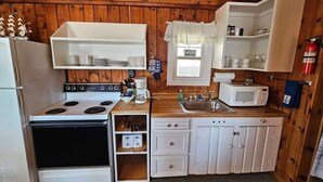 Cozinha compacta com fogão, micro-ondas e armários brancos.