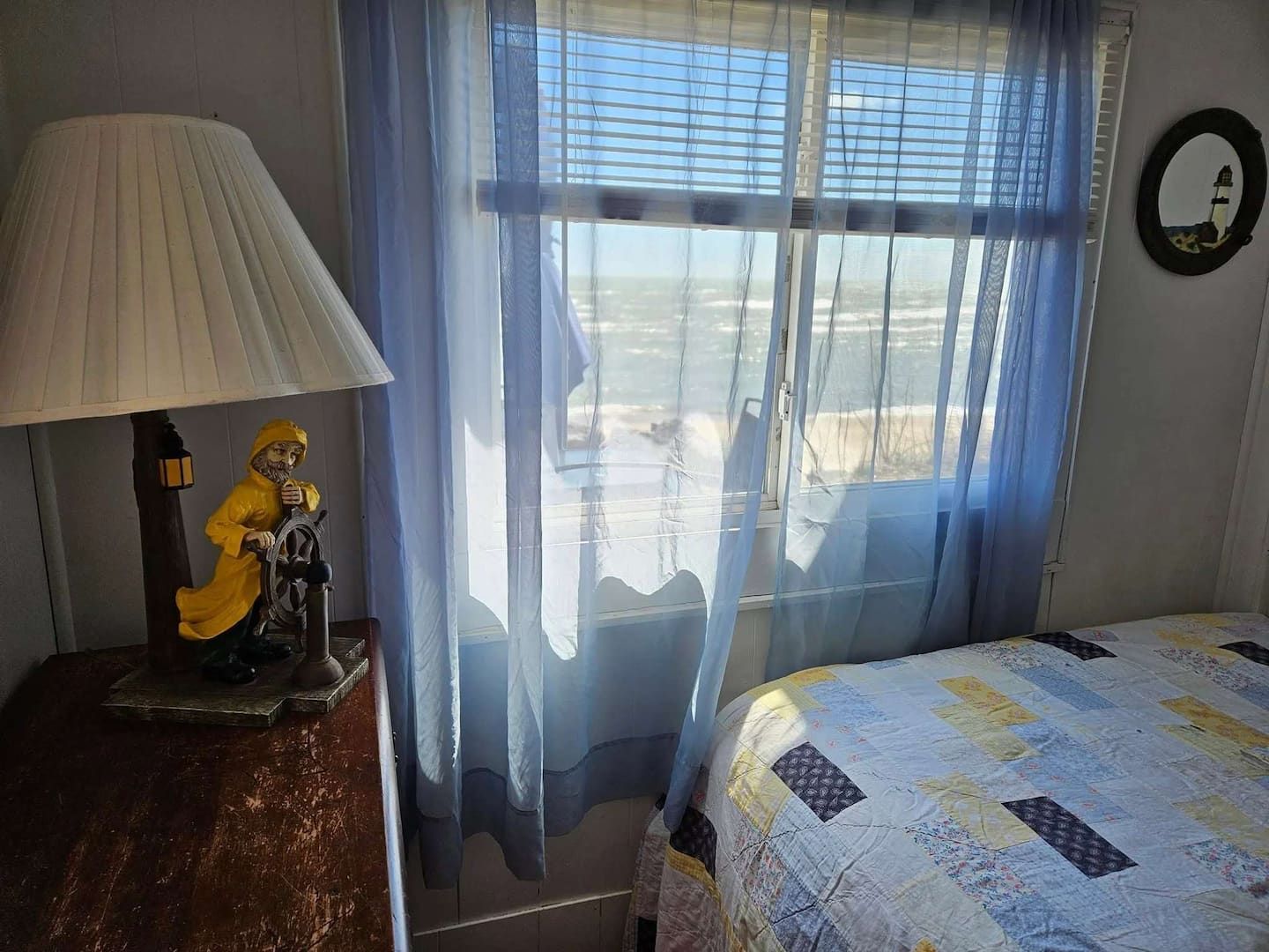 Una habitación con una cama, una lámpara, una estatua y una ventana con cortinas.