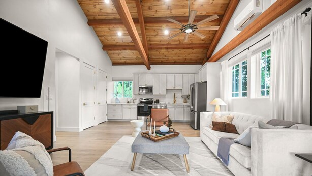 A spacious living area with a wooden ceiling, a flat-screen TV, a sofa, a coffee table, and a kitchen in the background. - New Cozy 2-bedroom studio in Walnut Creek with AC (walnut creek)