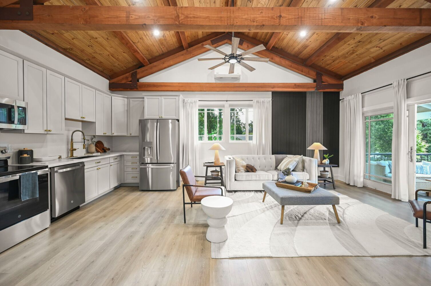A spacious kitchen with modern appliances, a dining area with a sofa and table, and a large window with a view.
