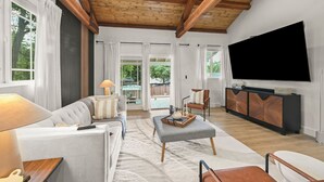 A modern living room with a sofa, ottoman, and a flat-screen TV mounted on the wall. - New Cozy 2-bedroom studio in Walnut Creek with AC (walnut creek)