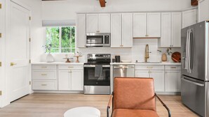 A modern kitchen with white cabinets, stainless steel appliances, and a leather chair. - New Cozy 2-bedroom studio in Walnut Creek with AC (walnut creek)