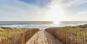 A sandy beach path leading to the ocean with a wooden fence on both sides. - Maison Terre Océan (Angles)