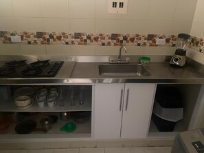 Eine Küche mit Gasherd, Spüle und einem Mixer auf der Arbeitsfläche.