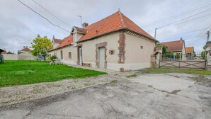 A two-story building with a red-tiled roof, a brick facade, and a small front yard with a bench and a table. - Le Nid d'Hirondelles (FONTAINE LES GRES)