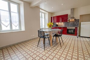 Eine Küche mit Esstisch, Stühlen, einem roten Schrank, einem Herd und einem Kühlschrank.