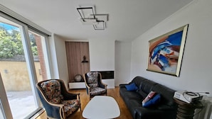 Uma sala de estar moderna com um sofá, duas poltronas, uma mesa de centro e um quadro na parede.