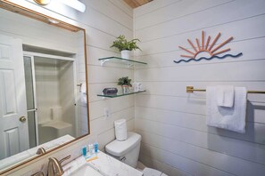 Un baño con inodoro blanco, lavabo con encimera de mármol, espejo con marco dorado y toallero con toalla blanca.