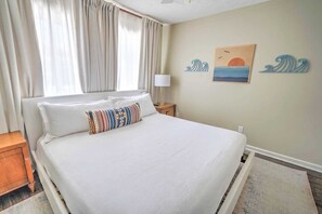 Un letto rifatto con lenzuola bianche, un cuscino decorato e un comodino in legno con una lampada.