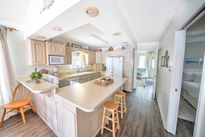 A spacious kitchen with a central island, wooden bar stools, and a microwave. - 076 Gulf Loop -  3 Bed/2 bath - Golf Cart Included - Stunning Views of St. Andrews St. Park! (Panama City Beach)