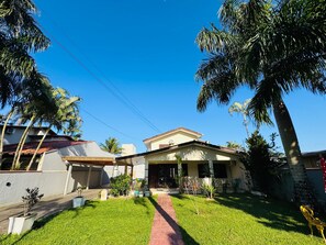 A residential house with a paved driveway, a front porch, and a well-maintained lawn. - Super house on the beach with pool, 60m from the sea, air conditioning, etc. (Guaratuba)