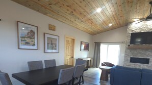 Un comedor con techo de madera, chimenea de piedra y obras de arte enmarcadas en las paredes.