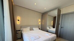 A hotel room with a large bed, bedside tables, a mirror, and a wardrobe. - 401 Tara-jre Jabal Al Lweibdeh With Stunning View (Amman)