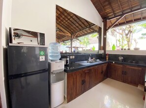 Cocina con refrigerador, dispensador de agua, microondas y gabinetes de madera.