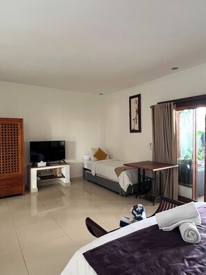 Una habitación de hotel con cama, televisión, escritorio y ventana con cortinas.