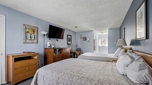 Een slaapkamer met twee bedden, een bureau, een televisie en een stoel.