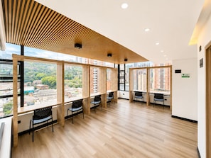 Un espacio de oficina moderno con ventanas amplias, listones de madera en el techo y múltiples puestos de trabajo.