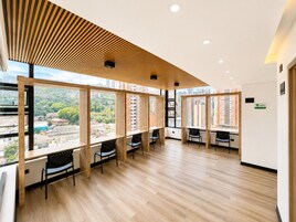 Un espacio de oficina moderno con ventanas amplias, listones de madera en el techo y múltiples puestos de trabajo.
