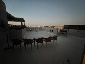 Une terrasse sur le toit, dotée d’un espace salon, d’un ventilateur et offrant une vue sur le paysage urbain.