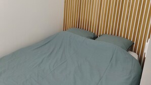 A single bed with a green bedspread, a wooden slat headboard, and a white wall. - 2 People | Near town center and beaches | Air-conditioned | Garden (Cavalaire sur Mer)