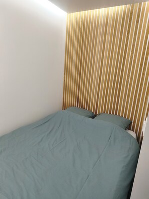 A single bed with a green bedspread, a wooden slat headboard, and a white wall. - 2 People | Near town center and beaches | Air-conditioned | Garden (Cavalaire sur Mer)
