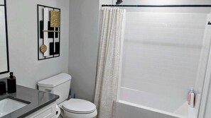 Een badkamer met toilet, wastafel en douchegordijn.