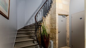 Eine Treppe mit Metallgeländer, ein Blumentopf, ein Mülleimer und eine Tür mit einem Schild.