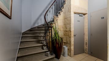 Un escalier avec une rampe en métal, un pot de fleurs, une poubelle et une porte avec une pancarte.